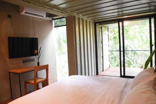 a bedroom with a bed and a desk and a television at River Pavilion, Kitulgala in Yatiyantota