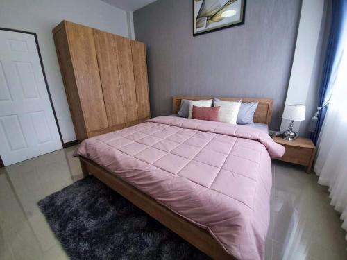a bedroom with a large bed with a pink comforter at ไอโฮมพัทยาเพลส in Pattaya Central