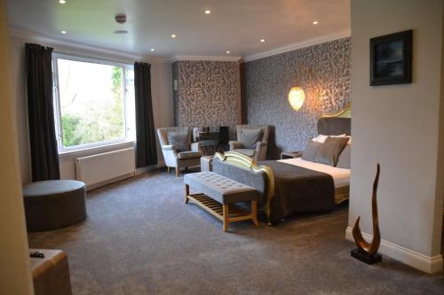 a hotel room with a bed and chairs and a window at The Popinjay Hotel in Larkhall