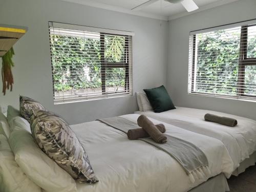 Un dormitorio con una cama grande con dos ventanas. en Eland Place Self Catering Guest House, en Beacon Bay