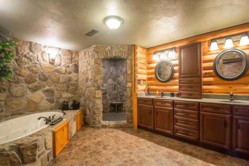 La salle de bains est pourvue de murs en bois, d'une baignoire et d'un lavabo. dans l'établissement Buffalo River Lodge (Yellville)- Lower Level, à Saint Joe