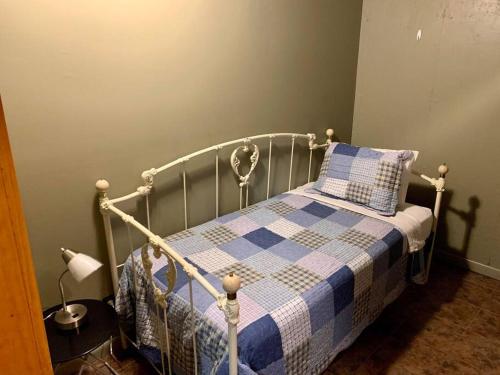 a bedroom with a bed with a blue and white checkered blanket at Buffalo River Lodge (Yellville)- Lower Level in Saint Joe