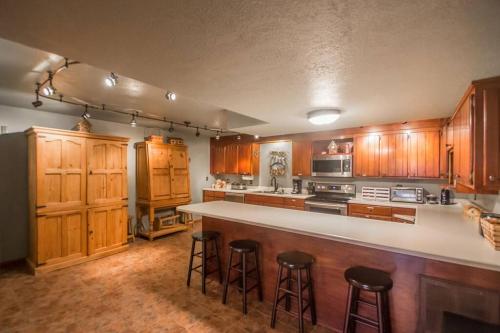 a large kitchen with wooden cabinets and bar stools at Buffalo River Lodge (Yellville)- Lower Level in Saint Joe