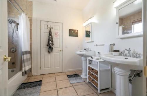 a white bathroom with two sinks and a shower at Hills of Studio City, your serene home away from Home in Studio City