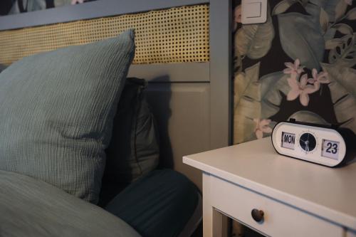 a clock sitting on a table next to a bed at Chez Marianne & Mathieu in Moustoir-Remungol