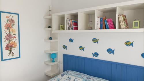 a bedroom with a bed with a blue headboard and books at Casa Mariuccia in Valledoria