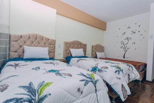 two beds in a room with white walls at PAKARINA HOUSE in Cusco