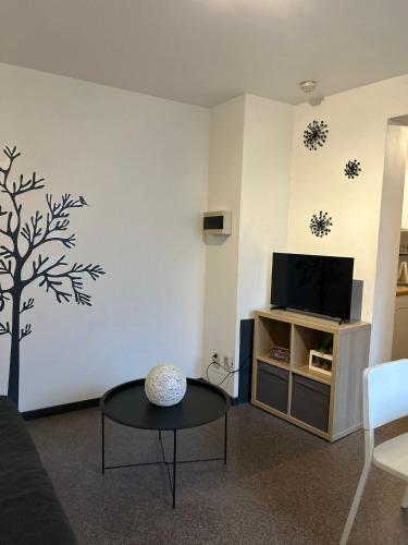 a living room with a table and a tv at Impasse 1 in Fosses-La-Ville