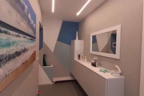 een badkamer met een wastafel en een schilderij aan de muur bij Aleph Guest House relax a due passi dal mare in Fertilia