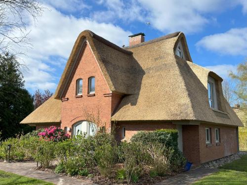 an old brick house with a thatched roof at Reetdach-Landhaus Mini Haubarg in Tating