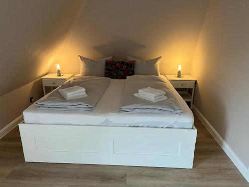 a white bed in a room with two night stands at Reetdach-Landhaus Mini Haubarg in Tating