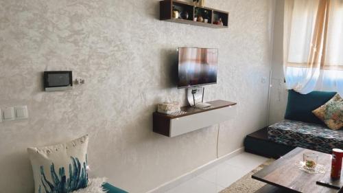 a living room with a couch and a tv on the wall at appartement plage mahdia sable dor in Kenitra