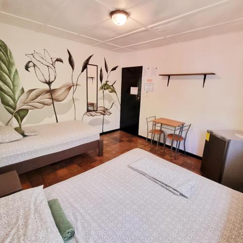 a room with two beds and a table and chairs at Casa Pura Vida Surf Hostel - Tamarindo Costa Rica in Tamarindo