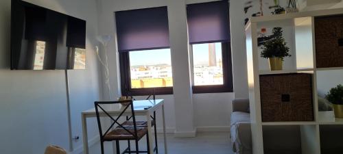 sala de estar con mesa, sillas y ventanas en Loft Triana Sevilla, en Sevilla
