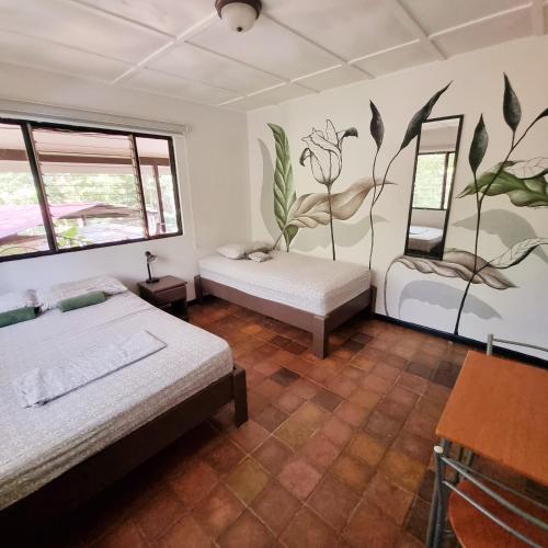 a bedroom with two beds and a mural on the wall at Casa Pura Vida Surf Hostel - Tamarindo Costa Rica in Tamarindo