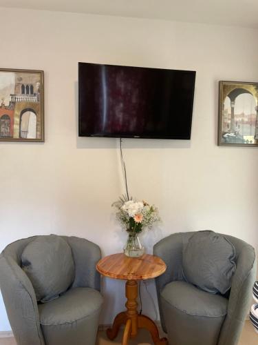 two chairs and a table with a tv on a wall at Appartment Martin in Westendorf
