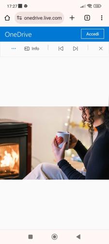 a woman holding a cup of coffee in front of a fireplace at B&B A casa di Carla in Castelsaraceno