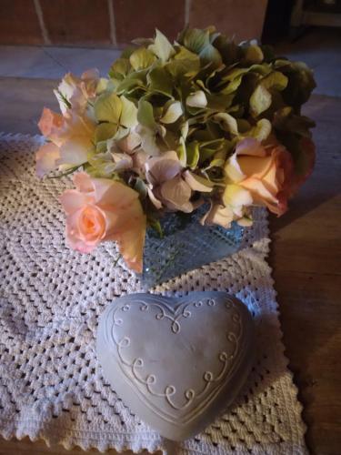 a vase with a bouquet of flowers next to a heart cookie at Gite de la Sauvetat in Auvillar