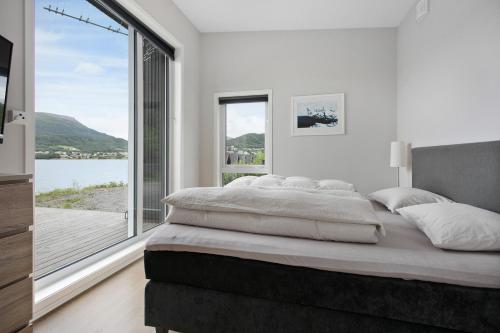 - une chambre avec un grand lit et une grande fenêtre dans l'établissement Fantastisk sommerhus i Tennfjord, ved Ålesund., à Tennfjord