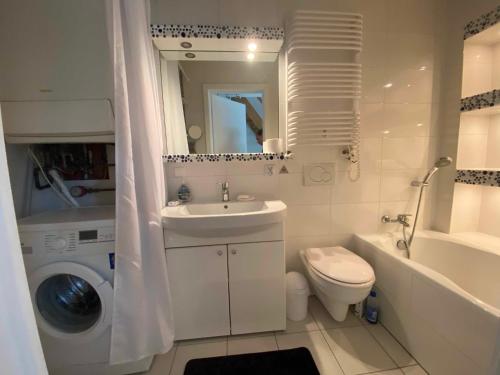 een witte badkamer met een wastafel en een wasmachine bij Kleine schöne Doppelhaushälfte in Częstochowa