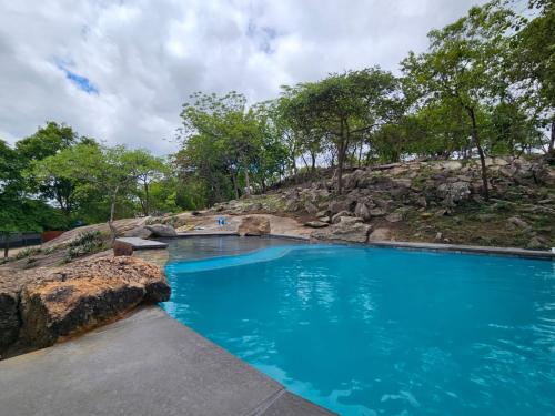 ein Pool aus blauem Wasser mit einem Hügel im Hintergrund in der Unterkunft GEORGE B BOUTIQUE LODGE in Tzaneen