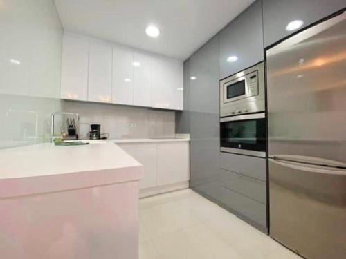 La Horadada的住宿－Appartement Mil palmeras，厨房配有白色橱柜和不锈钢冰箱