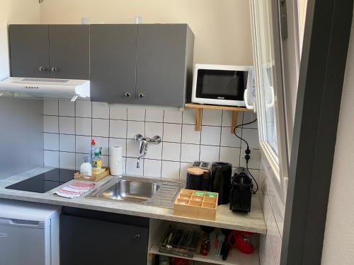 a small kitchen with a sink and a microwave at L'Eldorado Ruthénois - Garage & Terrasse in Rodez