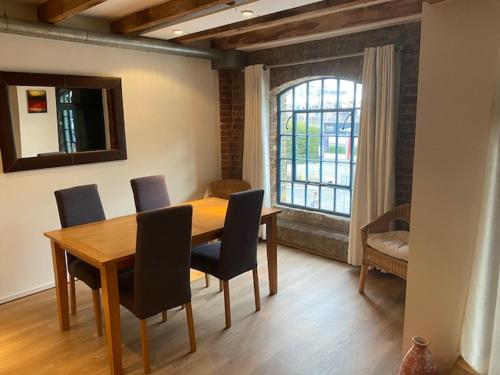 comedor con mesa, sillas y ventana en Apartment 3, Warehouse K, en Londres