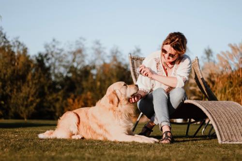 una mujer sentada en una silla acariciando a un perro en Siedlisko Nad Miedwiem en Stargard Szczeciński