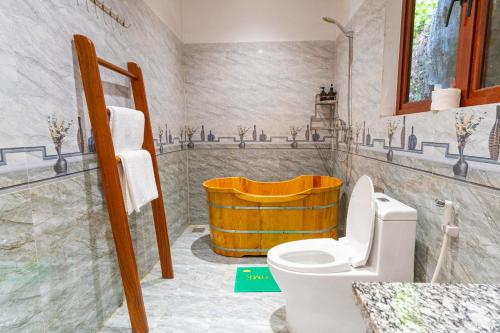 a bathroom with a toilet and a wooden tub at Green Mountain Homestay in Ninh Binh