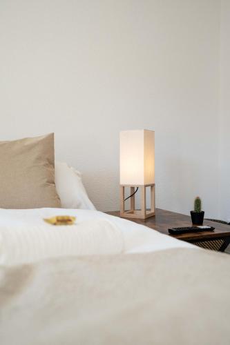 a white bed with a lamp on a table at Moderne Wohnung mit Parkplatz in Ostermundigen