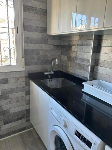 a kitchen with a sink and a washing machine at Punta Prima Palm Beach Apartment in Punta Prima