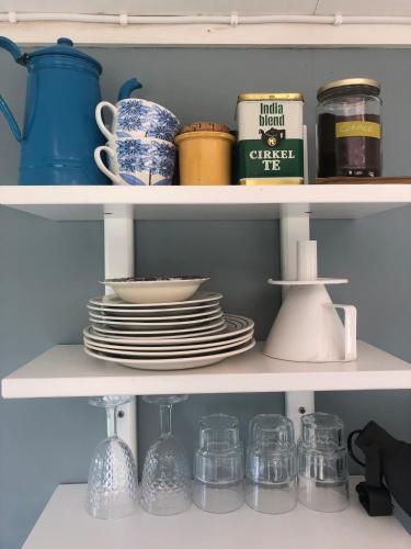 a shelf with plates and cups and dishes on it at Agundaborg Lake hut with a view in Agunnaryd
