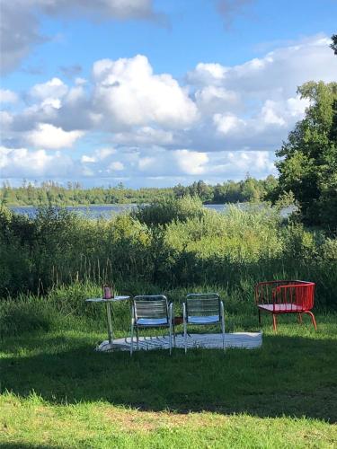two chairs and a table sitting in the grass at Agundaborg Lake hut with a view in Agunnaryd
