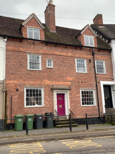 a brick house with a red door and trash cans at Studio Double. Own bathroom, shared kitchen in Bewdley