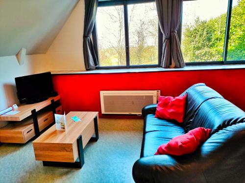 sala de estar con sofá azul y pared roja en Gîte 3 étoiles - Spacieux et confortable ancienne grange rénovée - Cantal Emotions Valette - Auvergne, en Valette