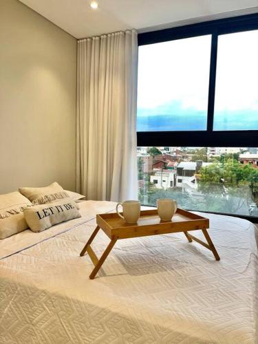 a bedroom with a bed with a table and a large window at Departamento de 1 ambiente in Encarnación