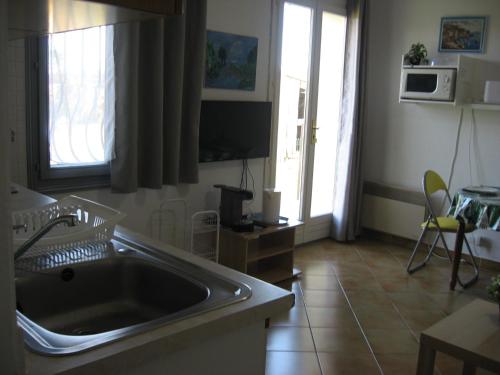 une cuisine avec un évier et une grande fenêtre dans l'établissement lumineux agréable T2 DE 32M2, à La Londe-les-Maures