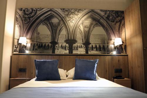 a bedroom with a bed with two blue pillows at Les Terrasses Poulard in Le Mont Saint Michel