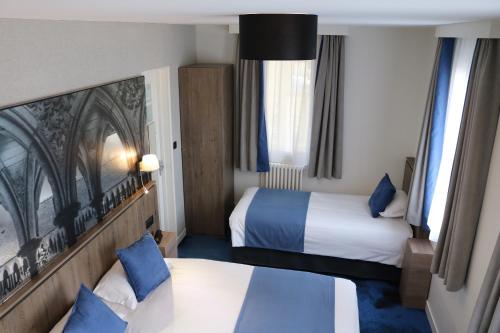 ein Hotelzimmer mit 2 Betten und 2 Fenstern in der Unterkunft Les Terrasses Poulard in Le Mont Saint Michel