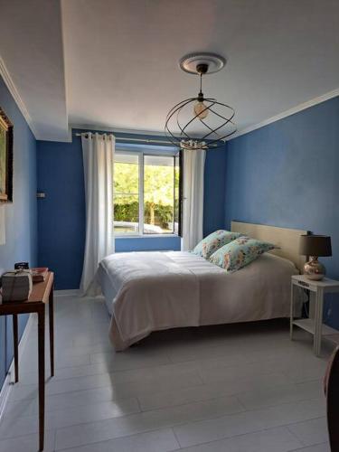 une chambre bleue avec un lit et une fenêtre dans l'établissement Gîte Marguerite - Au coeur de la campagne, à La Petite-Boissière