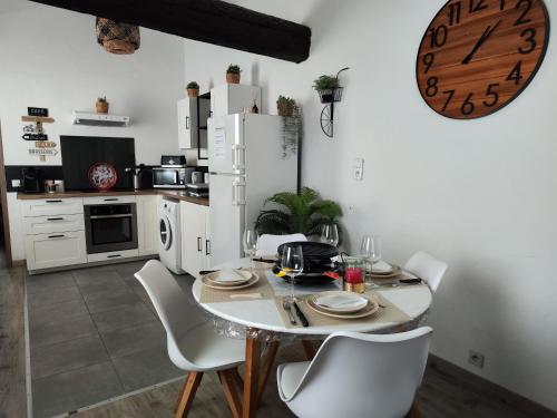 a kitchen with a table and chairs and a clock at Appartement de Charme L'Isle-sur-la-Sorgue sur la Sorgues in LʼIsle-sur-la-Sorgue