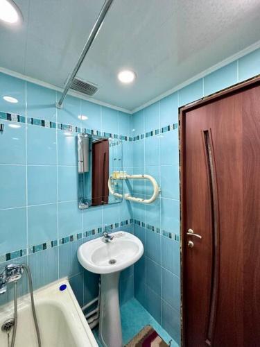 baño de azulejos azules con lavabo y bañera en Аренда с Самостоятельным Заездом, en Pavlodar