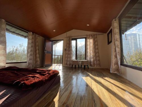 a bedroom with a large bed and large windows at MANDAP COTTAGE & CAFE in Nagar