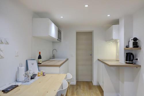 une cuisine avec des armoires blanches et une table en bois dans l'établissement Cujas, à Toulouse