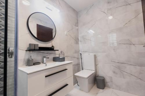 a bathroom with a sink and a mirror and a toilet at The Valley Villa in Accra