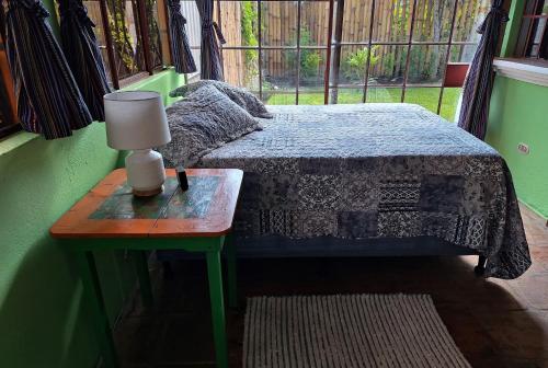 a bedroom with a bed and a table with a lamp at Sweet little cottage at Lake La Laguna in San Pedro La Laguna