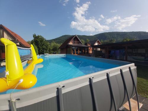 een groot zwembad met een gele glijbaan en een huis bij Kuća za odmor "DRINSKI KONAK" - Zvorničko jezero - Drina in Zvornik