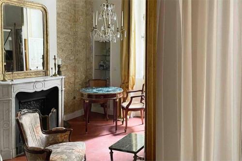 - un salon avec un lustre, une table et un miroir dans l'établissement Studio de charme au cœur de l’Île St Louis, à Paris