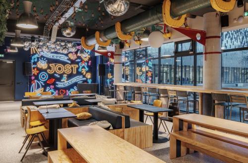 ein Restaurant mit Holztischen und -stühlen und einem Wandbild in der Unterkunft JOST Hôtel Le Havre Centre Gare in Le Havre